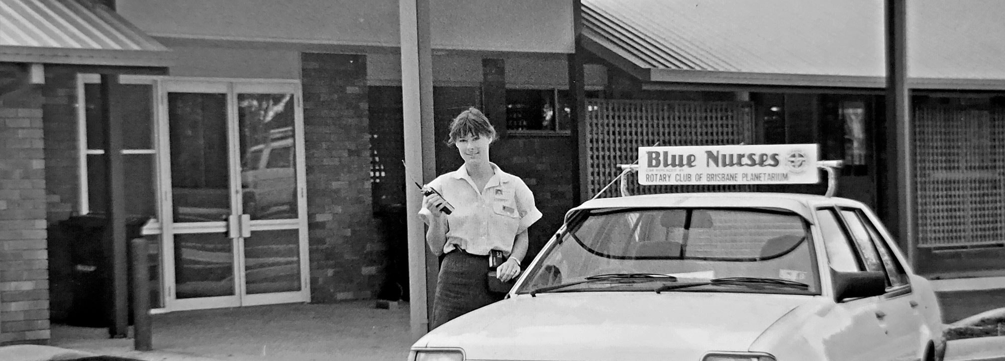 Black and white photo of a woman next to a car saying "Blue nurses"