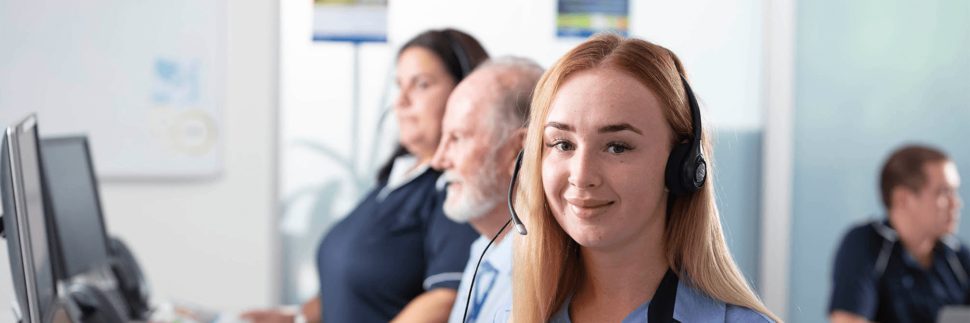 Lady in call centre wearing headset smiling at camera