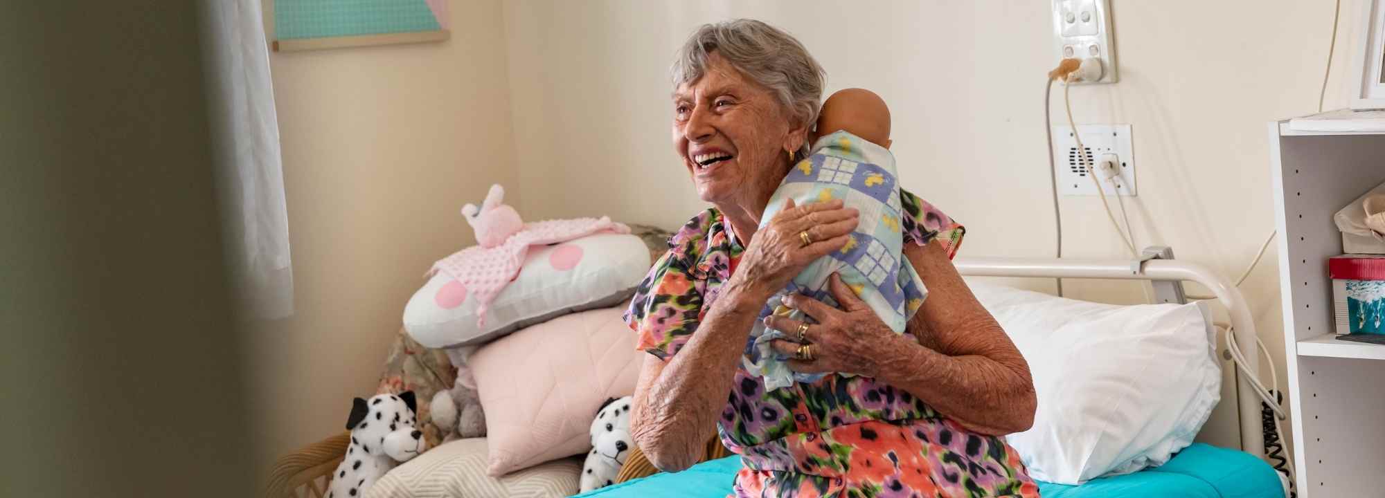 An older woman holds a baby in an aged care facility