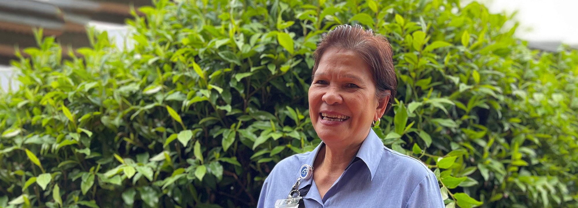 Blue Care employee standing in garden smiling at camera