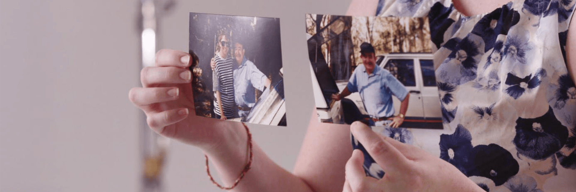 Happy memories of a much-loved dad Hands hold family photos of a young woman and her dad standing by a car in the bush.