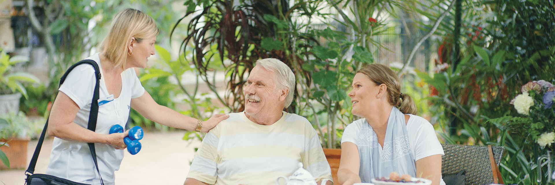 An older man and his daughter smiling at a Blue Care carer
