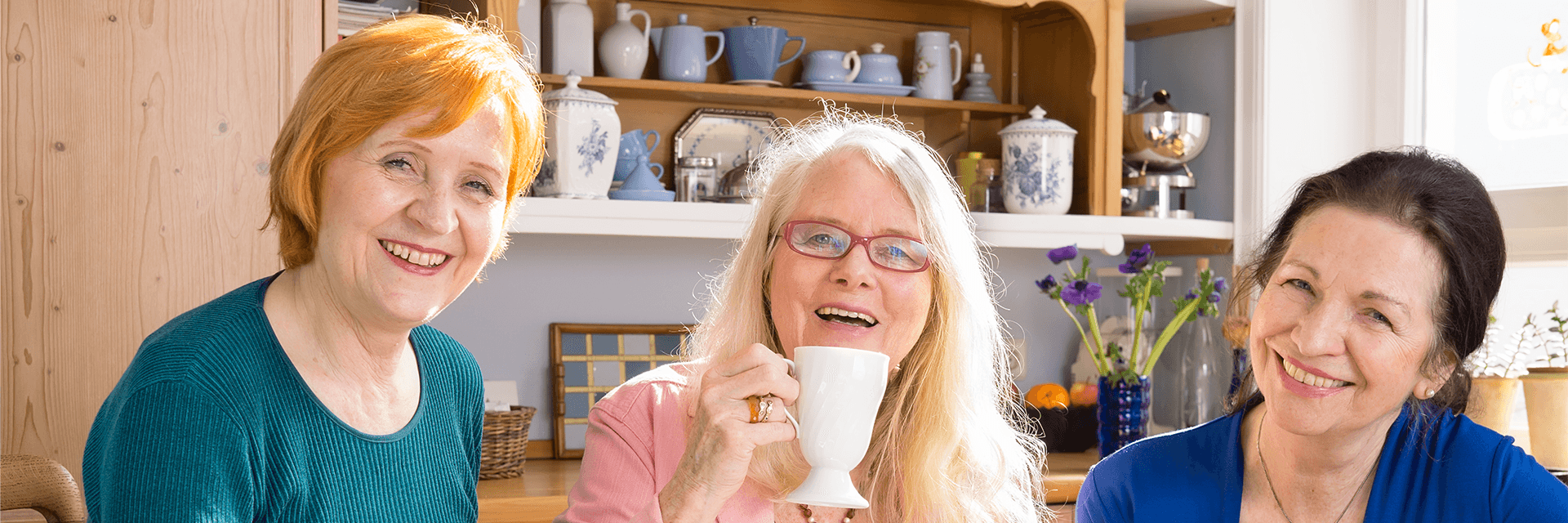 Three friends smiling at camera while having morning tea