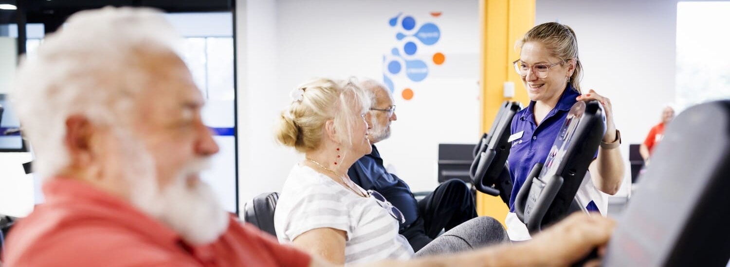 A Blue Care employee assists an older man with exercise