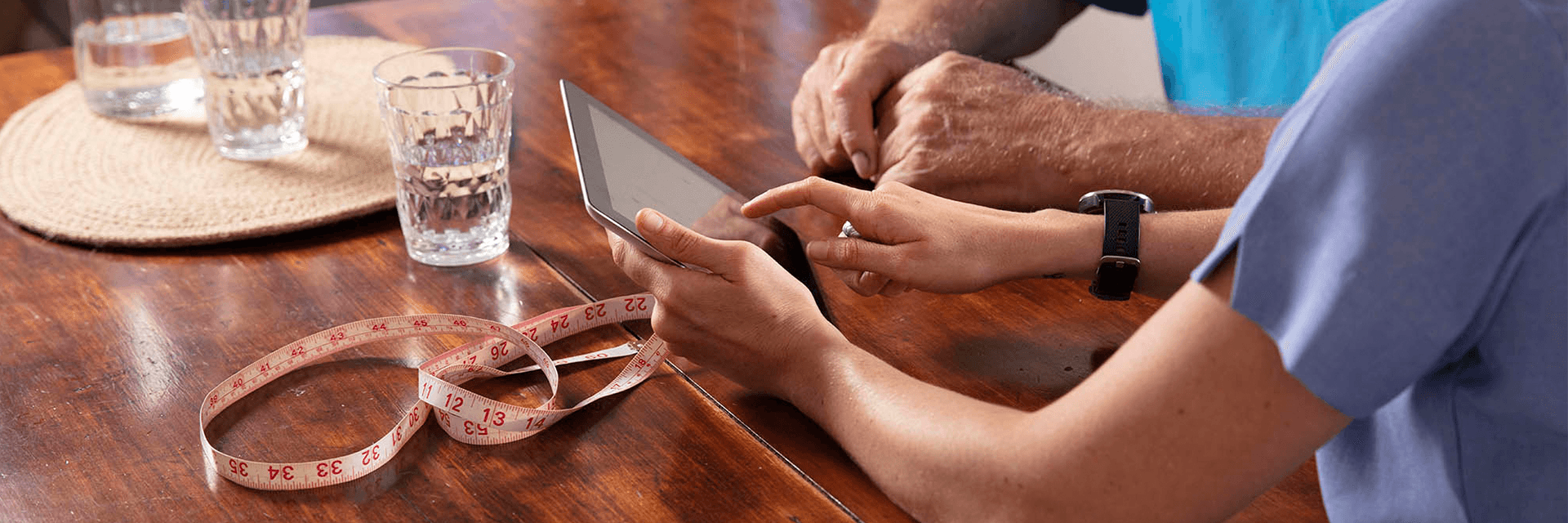 A Blue Care employee and older gentlemen review a digital tablet