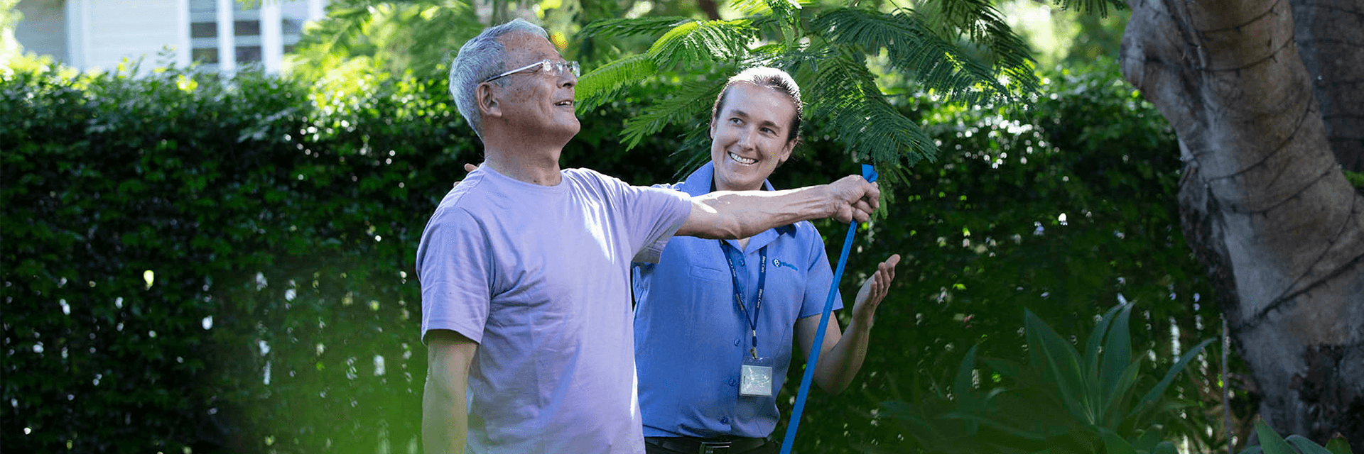 A Blue Care employee assists an older man with exercise
