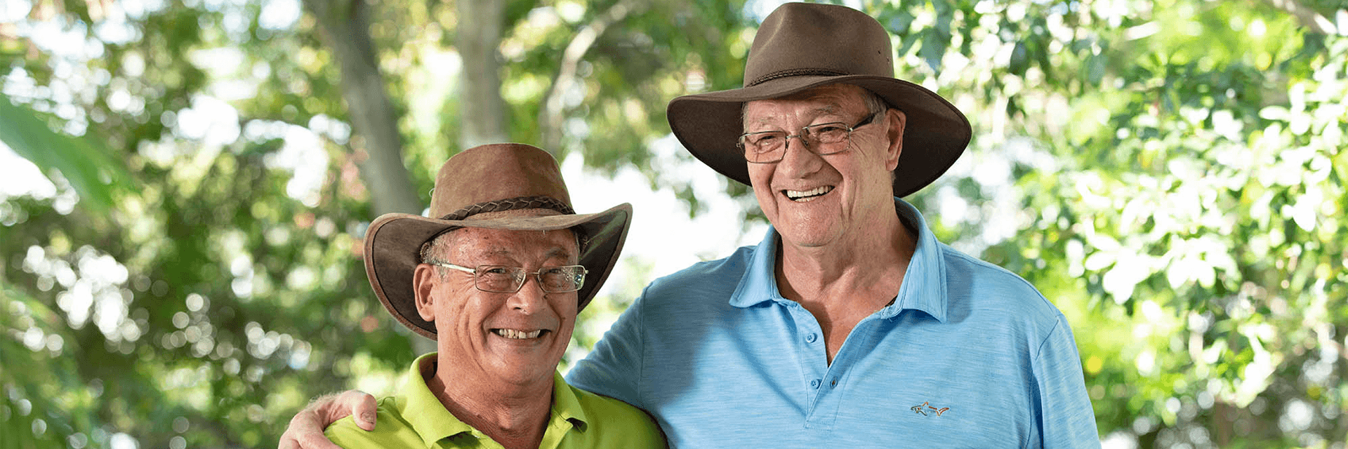 Two older gentlemen hugging and smiling at camera