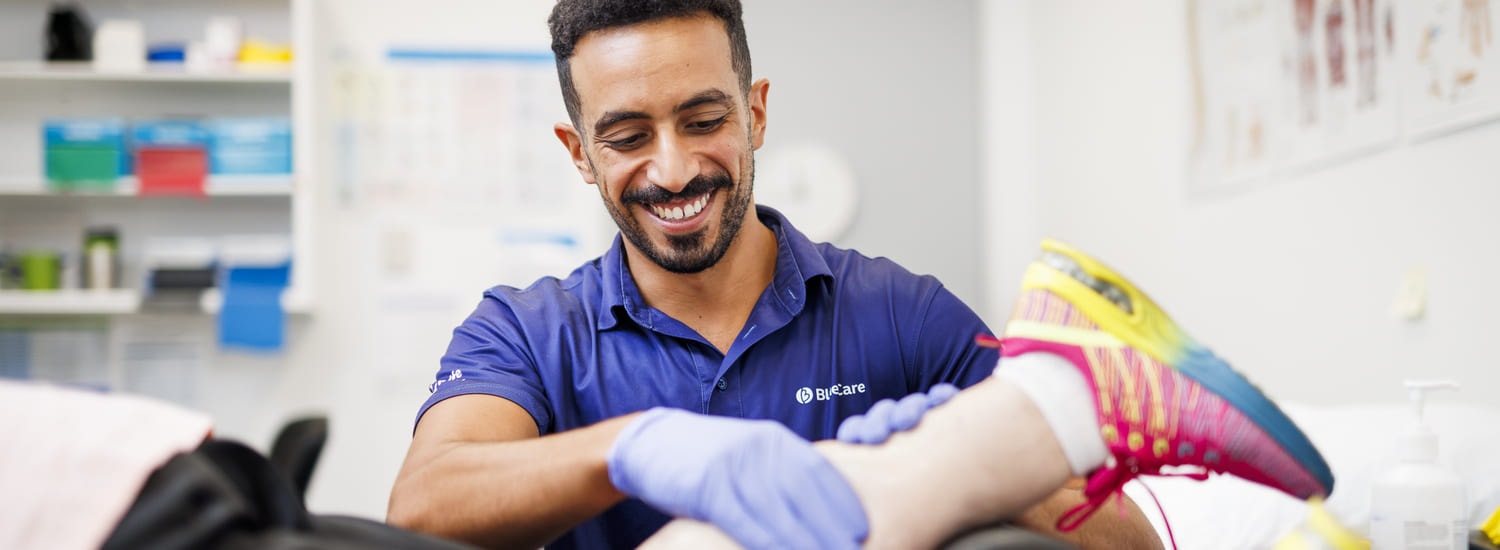 A BlueCare employee assists an older person with exercise