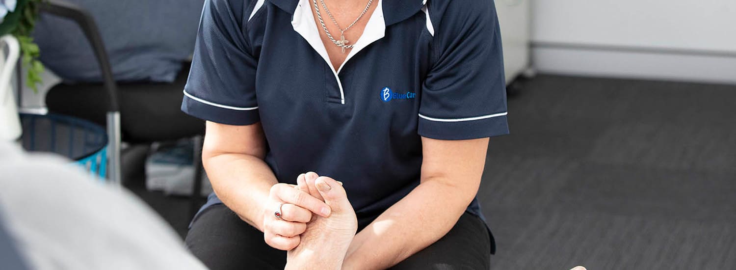 A BlueCare podiatrist performs an assesment on a client's foot