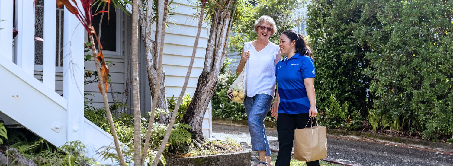 A BlueCare employee assist an older lady with shopping