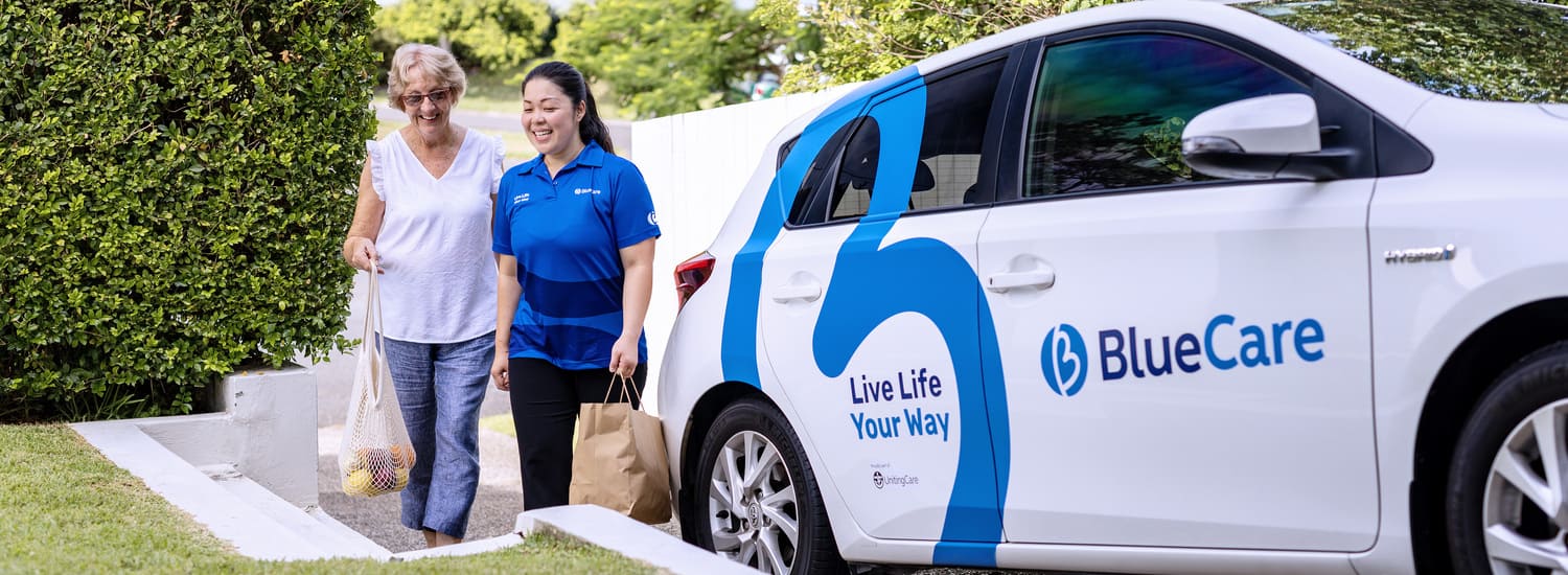 A BlueCare employee helps and older lady shopping