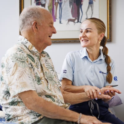 A BlueCare employee with an older gentlement smiling