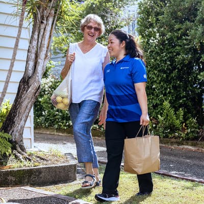 A BlueCare employee assist an older lady with shopping