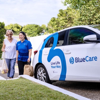 A BlueCare employee helps and older lady shopping