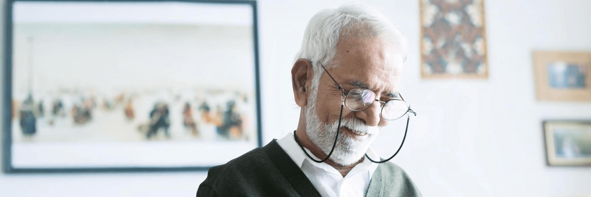 An older man looking down at a piece of paper with a smile on his face