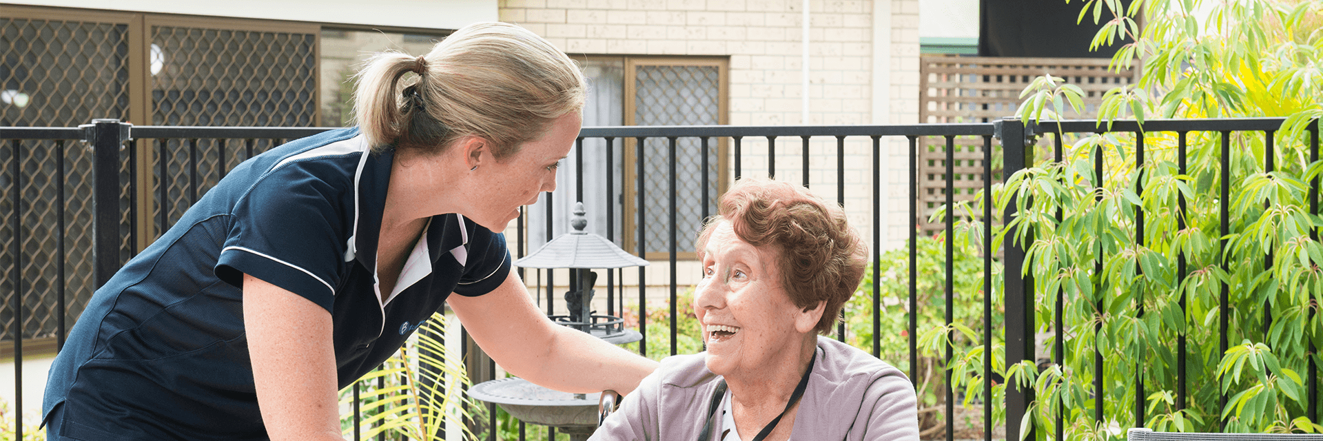 Time for a cuppa at Blue Care Bethania Haven A woman who works at Blue Care Beenleigh Bethania Haven Aged Care Facility brings a cup of coffee to an older lady sitting at an outdoor table.