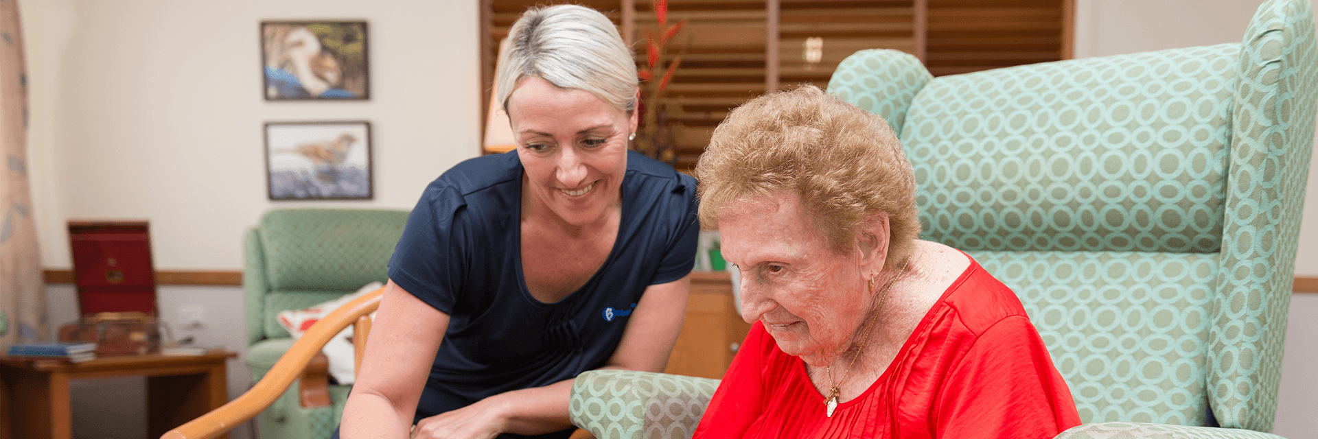 Puzzle time at Blue Care Caloundra Aged Care Facility An older lady in a red shirt enjoys a puzzle with a woman who works at Blue Care Caloundra Aged Care Facility.