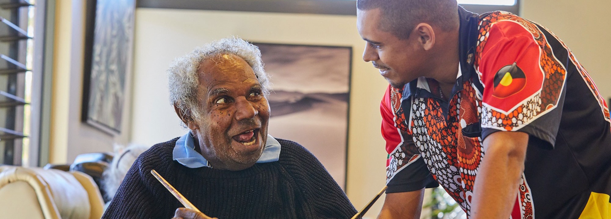 Two First Nations men work on a painting together at Pinangba Hollingsworth Elders Village.