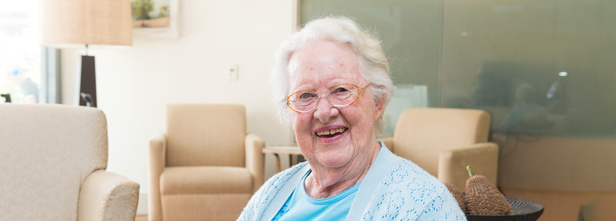 A Blue Care client sitting in a common area smiling at camera