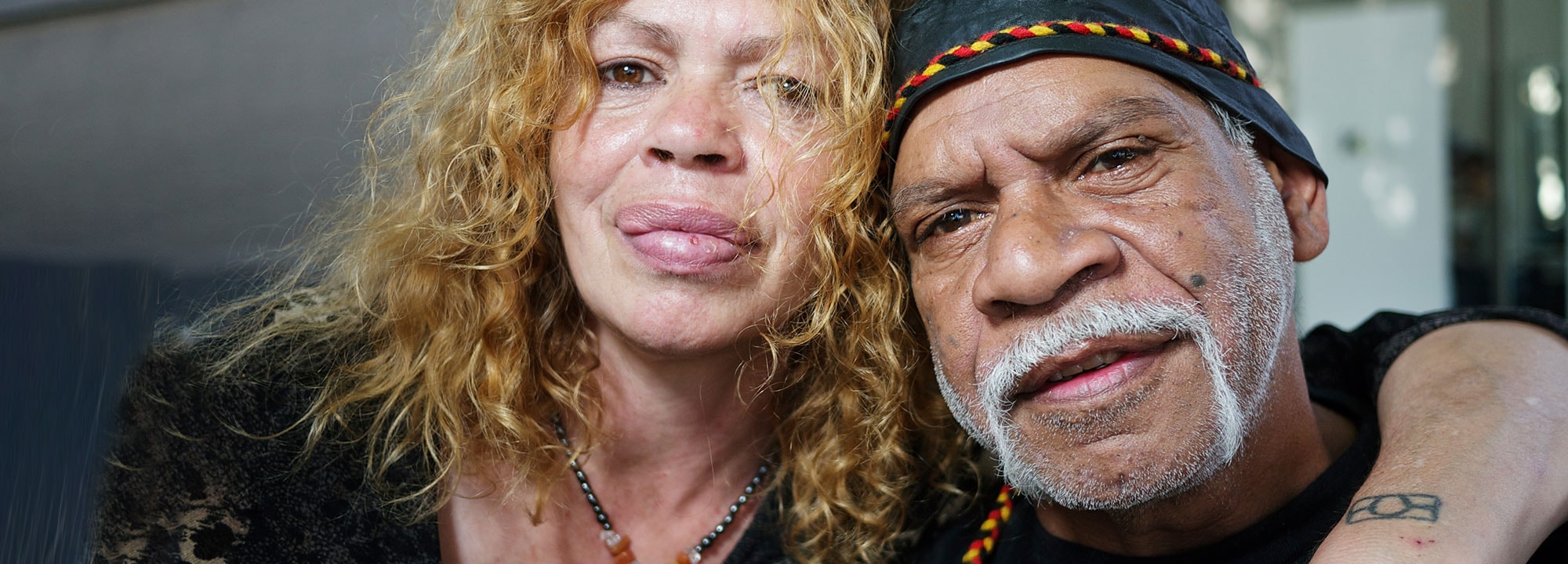 A First Nations woman puts her arm around a First Nations man at Pinangba Ny-Ku Byun Elders Village.