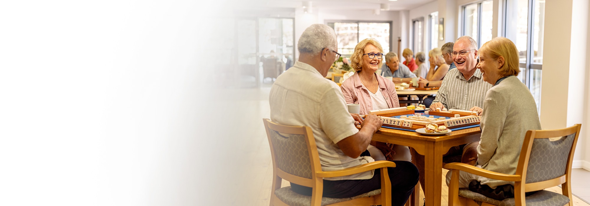 Two couples sitting at a table at a retirement living resort playing a board game
