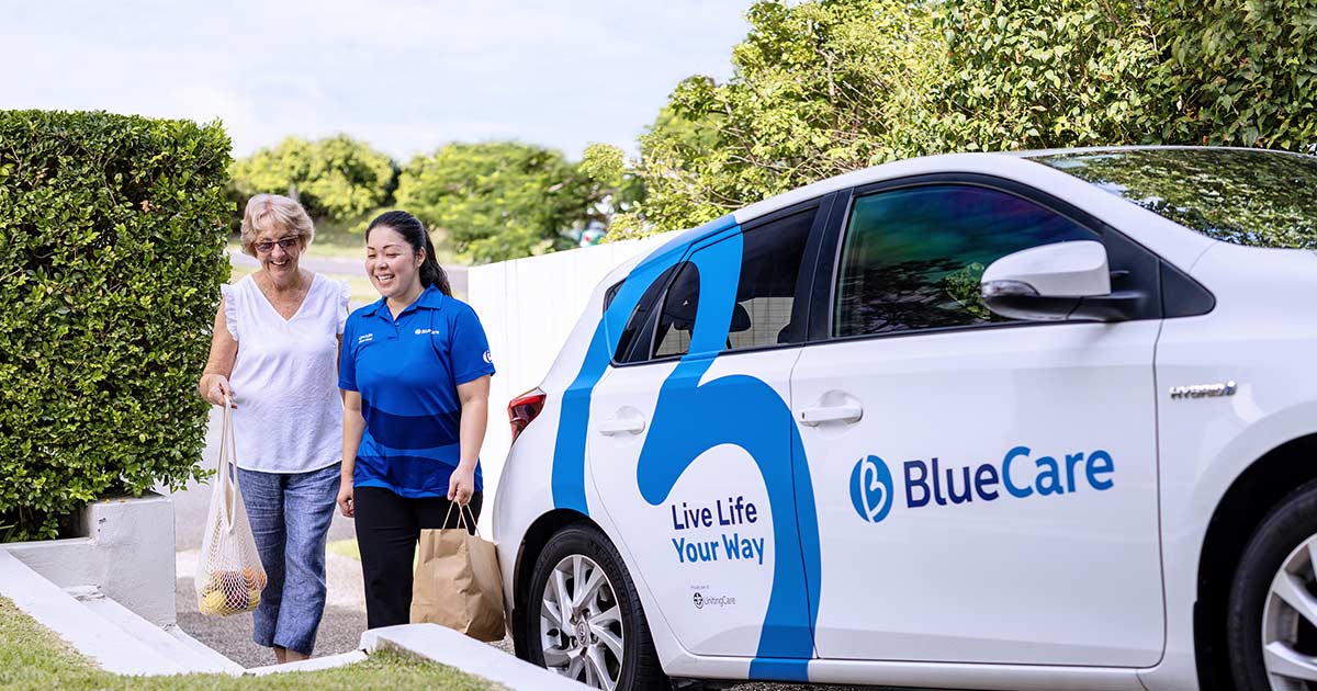 BlueCare activity officer Livia Kaminari walks with an elderly client.