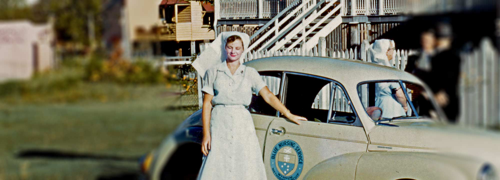 Historical image of first BlueCare nurse standing beside a company vehicle