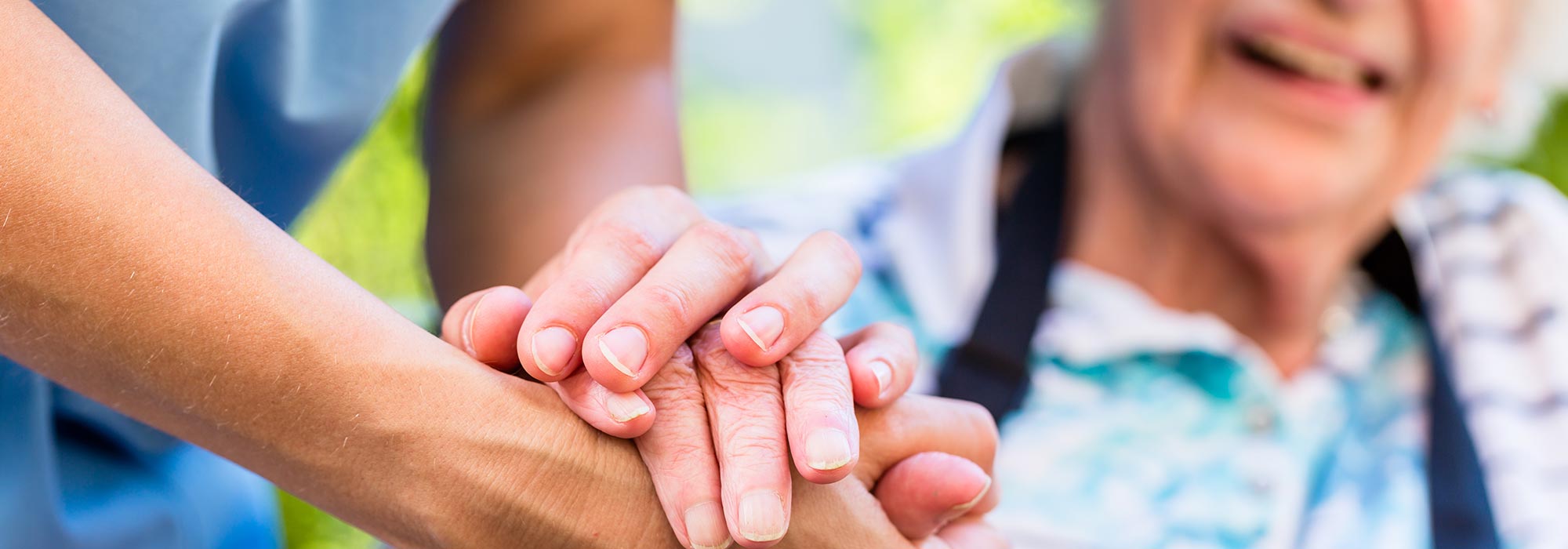 Close up shot of carer and elderly patient holding hands