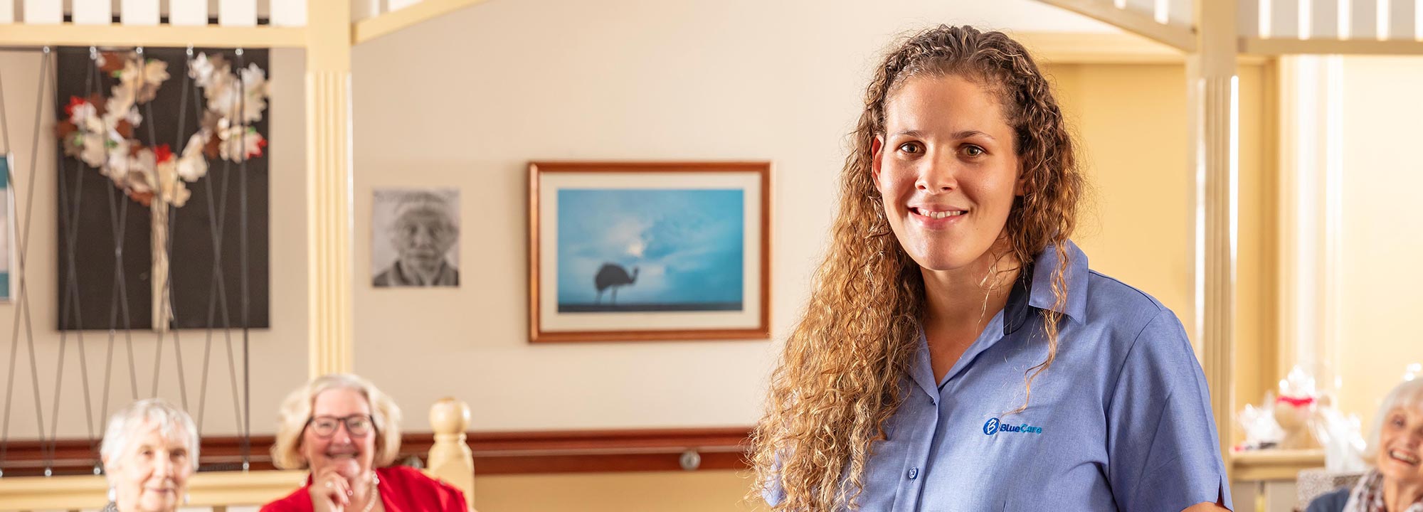 BlueCare staff member smiling and looking into the camera inside of a home